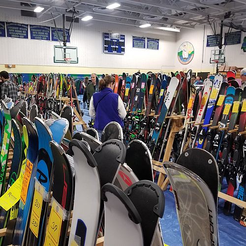 Photo of a ski swap with people looking at lots of skis