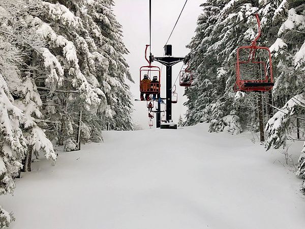 Photo of a red double chairlift on a snowy day