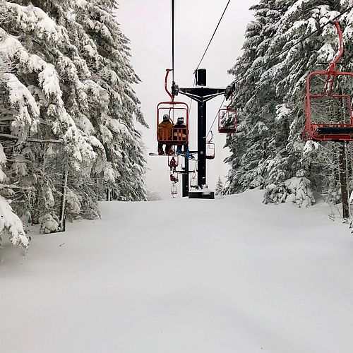 Photo of a red double chairlift on a snowy day