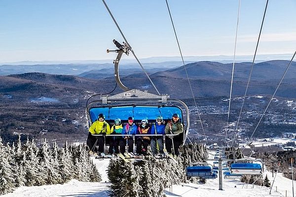 Image of blue bubble chairlift with skiers on it at Mount Snow in Vermont.