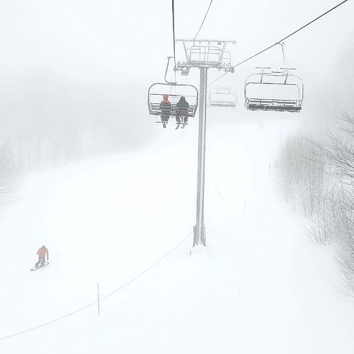 Quad chairlift ascends during a snowy day