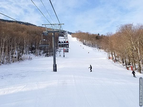 Photo of skiers and riders on the Liftline trail under the quad chairlift