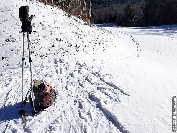 Photo of ski poles, backpack and Nordic ski tracks in the bright sun