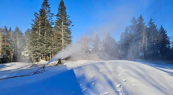 Making snow on a ski slope under a blue sky
