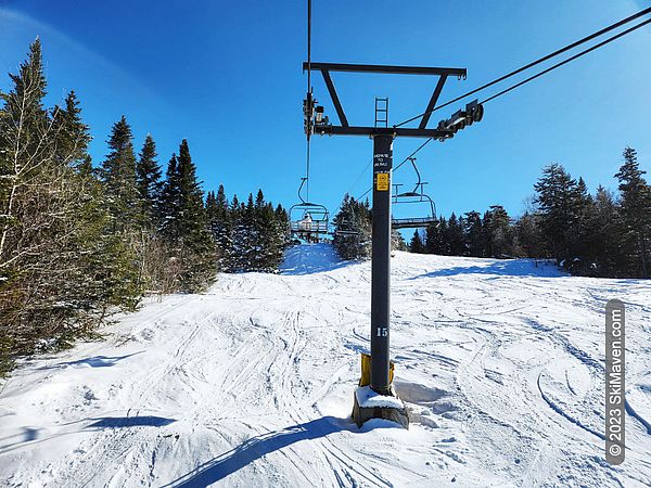 Fresh snow and blue sky seen from a quad chairlift
