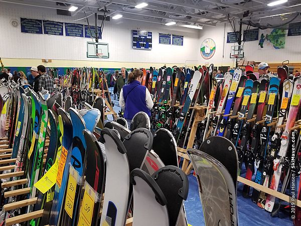 Photo of a ski swap with people looking at lots of skis