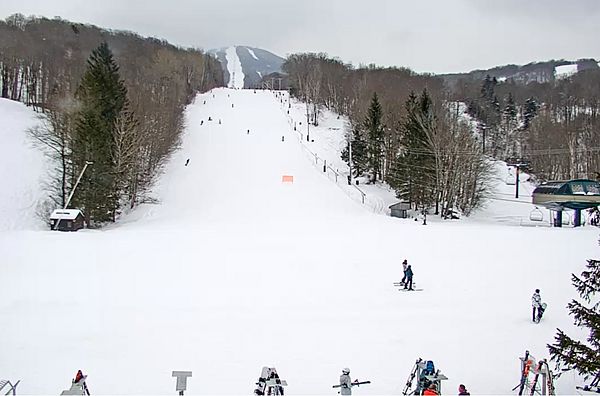 View looking up a wide ski slope with skiers