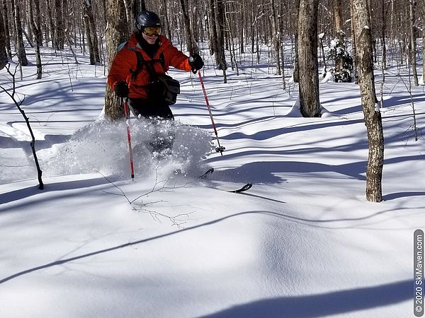 Photo of a telemark skier breaking through the snow as he turns