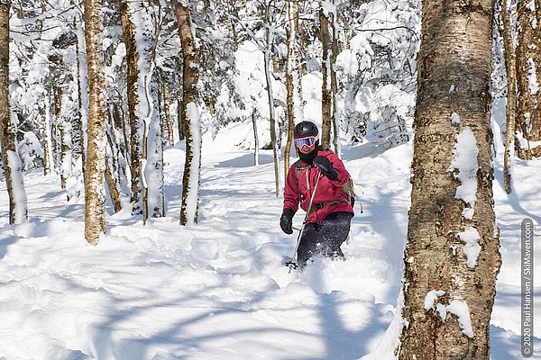 Photo of a skier smiling and skiing in the powder