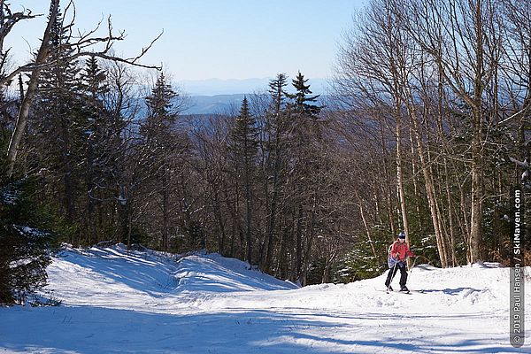 Photo of a skier using skins to climb up a trail