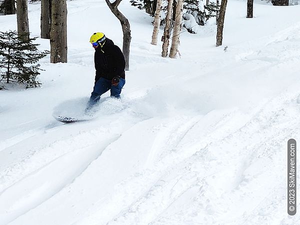 A snowboarder plows through some snow