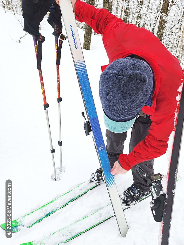 Skier rubs hard wax onto bottom of skis