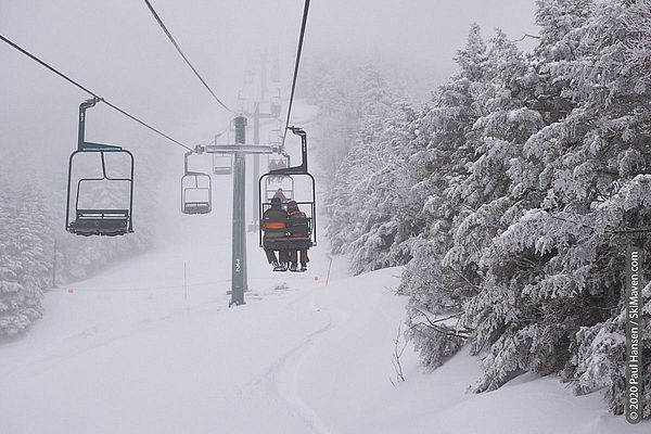 Photo of two people riding a long double chairlift