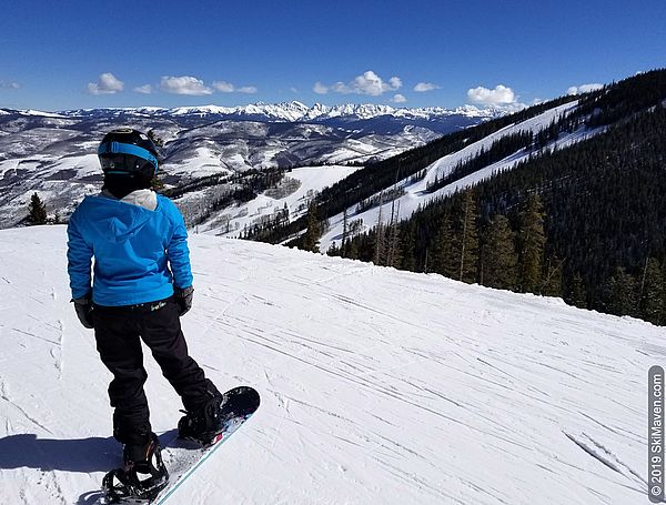 Snowboarder admires mountain views from Grouse Mountain at Beaver Creek, Colorado