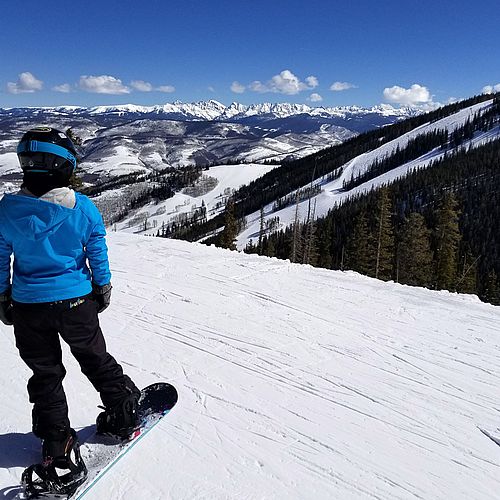 Snowboarder admires mountain views from Grouse Mountain at Beaver Creek, Colorado