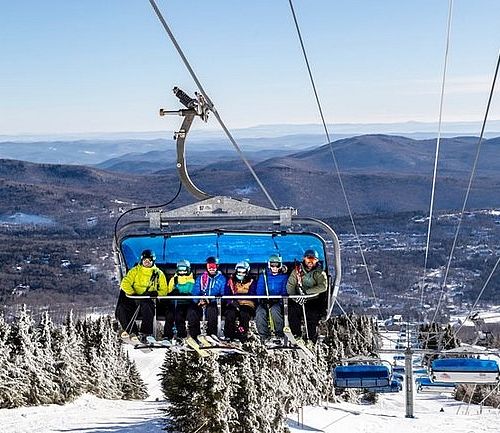 Image of blue bubble chairlift with skiers on it at Mount Snow in Vermont.