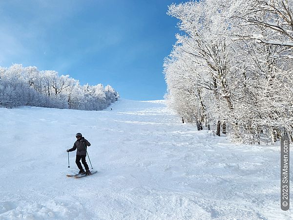 Skier descends down a wide ski slope