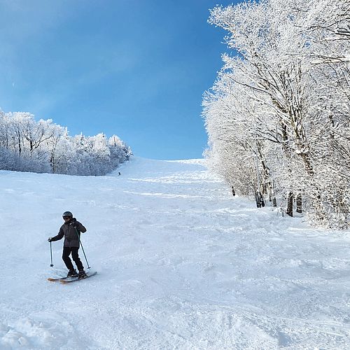 Skier descends down a wide ski slope