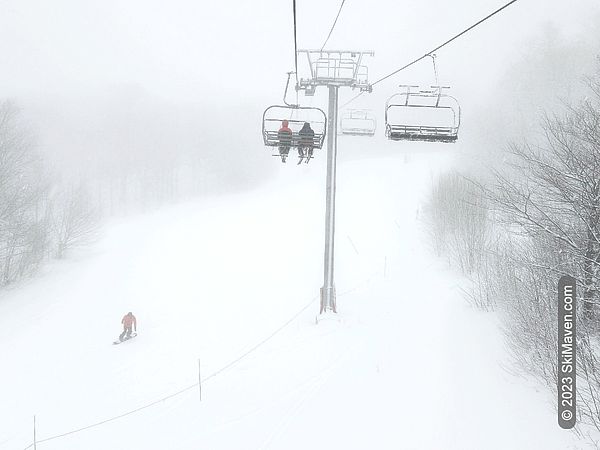 Quad chairlift ascends during a snowy day