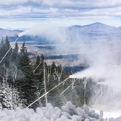 Snowmaking guns blow snow on a ski trail