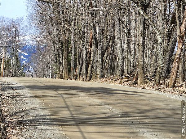 Photo of a dirt road with a snowy ski trail in the distance