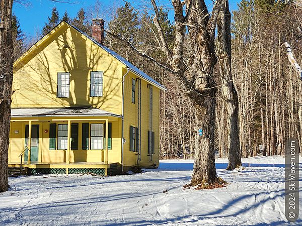 Mustard-yellow building with ski tracks passing by it