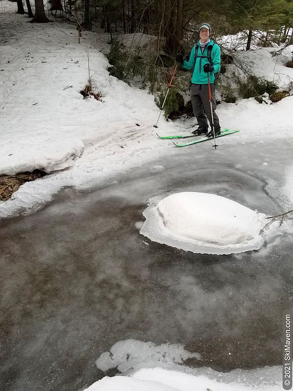 Photo of a skier standing on the edge of a melting stream