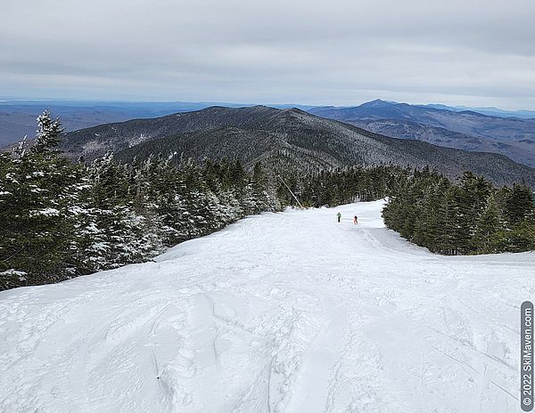 Photo looking down a snowy ski slope atop Mt. Ellen looking at mountain view