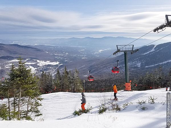 Photo of two skiers and red gondola cars