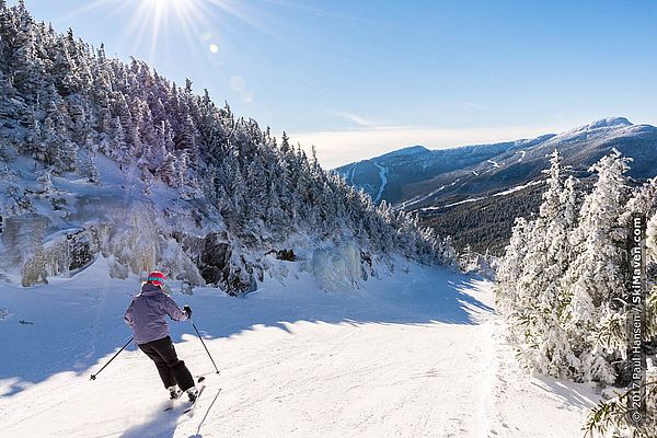 Photo of skier making turns at Smugglers' Notch in sunshine with mountain view