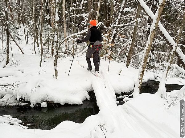 Photo of skier crossing an open stream