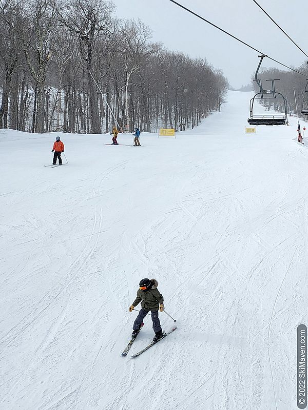 Photo of a child making a snowplow and other skiers nearby