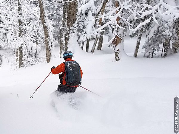 Photo of a skier plowing through powder and leaving a wake