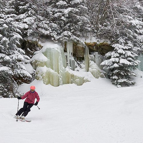 Photo of a skier turning in front of a frozen waterfall