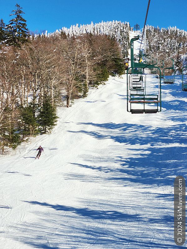 Skier skiing below a double chairlift